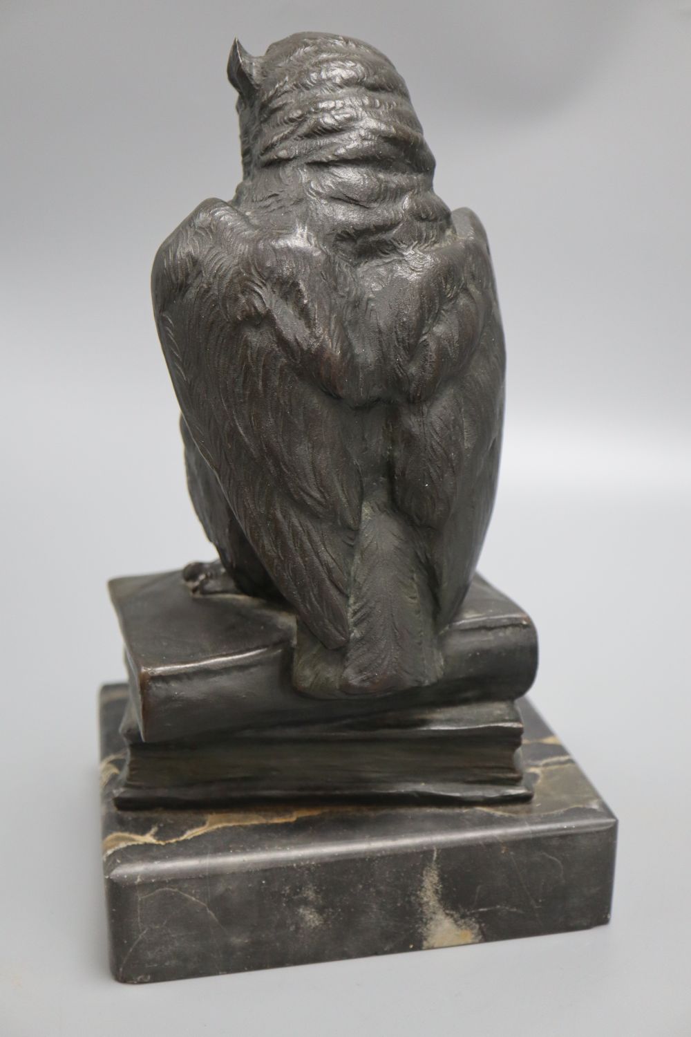 An early 20th century German bronze of an owl, with glass eyes, perched on a stack of two books, on marble base, height 26cm